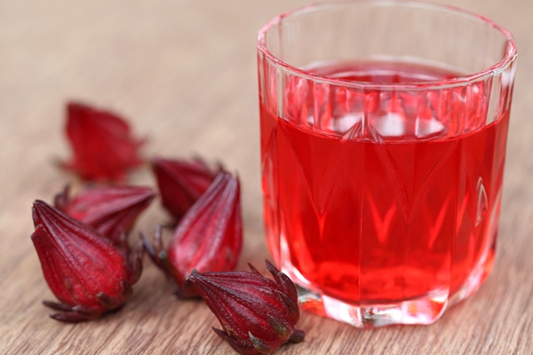 closeup of roselle with drink over wooden surface - Суфле из каркаде