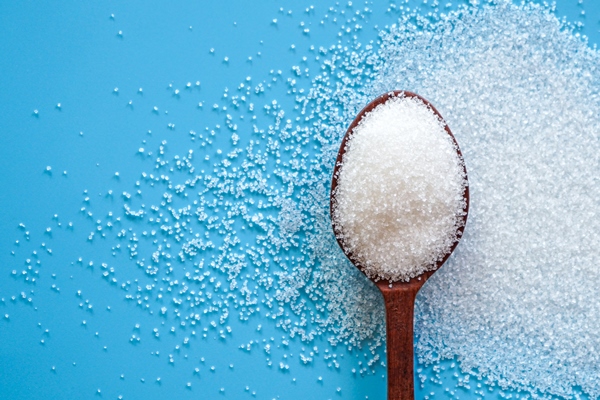 flat lay of white sugar in wooden spoon on blue background with copy space - Манник в мультиварке