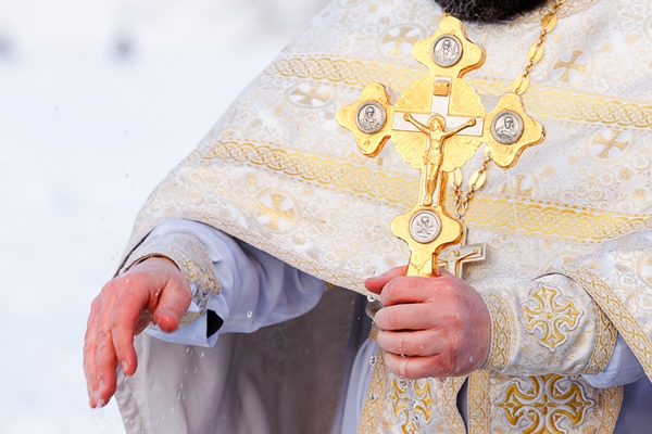 gold cross in the hands of a priest close up time to consecrate the water - Кулинарные традиции празднования именин