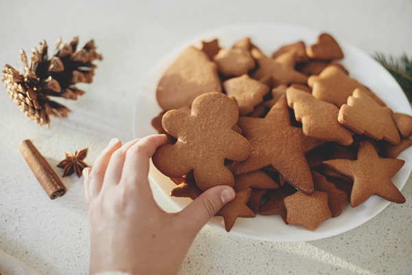 hand holding delicious gingerbread cookie against plate with cookies modern countertop warm sunlight baked fresh christmas gingerbread cookies atmospheric holiday time - Советы домашнему кондитеру: мука пшеничная