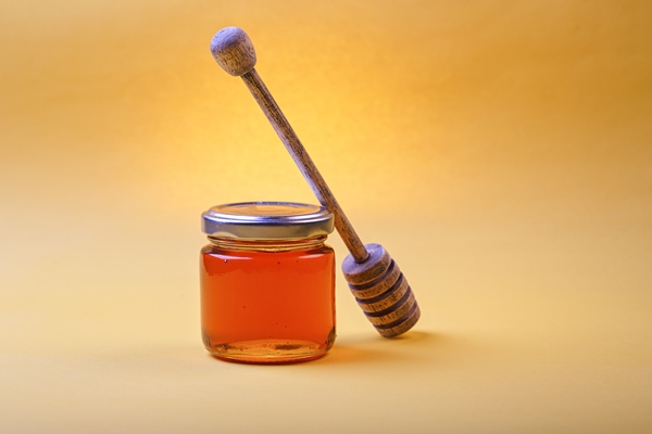 honey background sweet honey in the comb glass jar and a spoon for honey on the table light background - Апельсиновые оладьи, постный стол