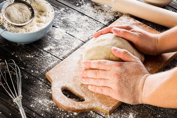 male hands kneading dough on sprinkled with flour table - Борканник