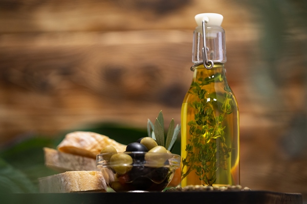 olives and bottle of olive oil on wooden background - Цукини на гриле с шалфеем