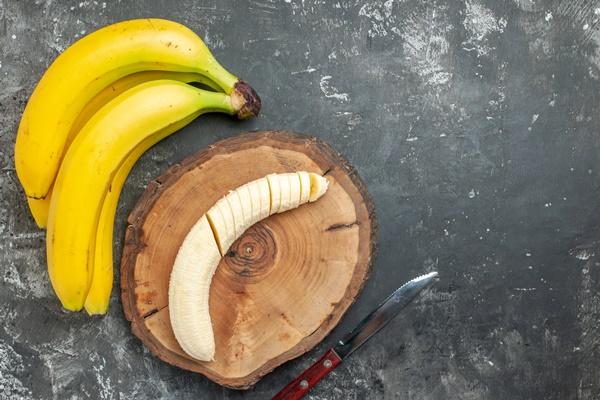 overhead view nutrition source fresh bananas bundle and chopped on wooden cutting board knife on gray background 1 - Оладьи с изюмом, постный стол