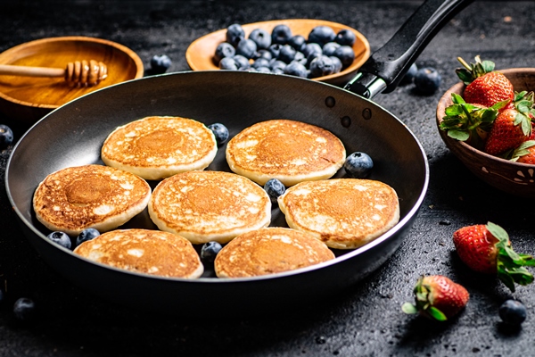pancakes in a frying pan with fresh berries and honey - Оладьи с изюмом, постный стол
