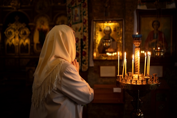 people lighting candles in church in celebration of greek easter - Кулинарные традиции празднования именин