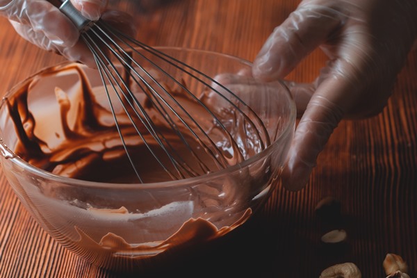picture of whisk with chocolate for cake preparation sweet cake glaze home made process with cocoa melt together to create a glaze for sweet cake and chocolate close up - Напиток молочный из кэроба