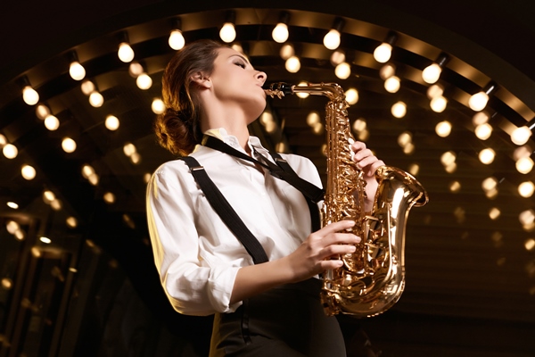 portrait of gorgeous brunette model woman in fashionable formal suit with saxophone playing on restaurant - Банкет