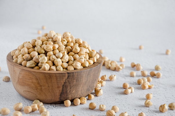 raw chickpeas on a wooden bowl on a light surface chickpeas is nutritious food healthy and vegetarian food horizontal copy space - Запечённый нут