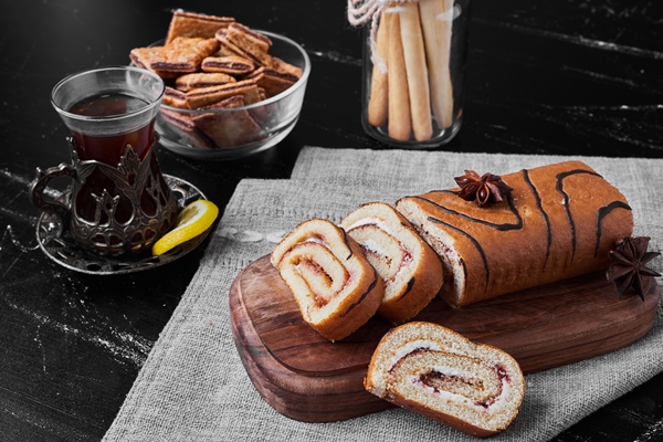 roll cake sliced on a wooden board and served with a glass of tea - Хозяйке на заметку: словарь кондитера