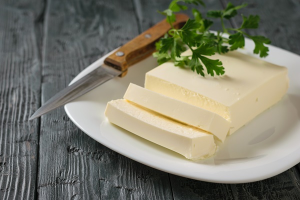 sliced serbian cheese with a knife and parsley leaves on a black wooden table - Картофельная запеканка в мультиварке