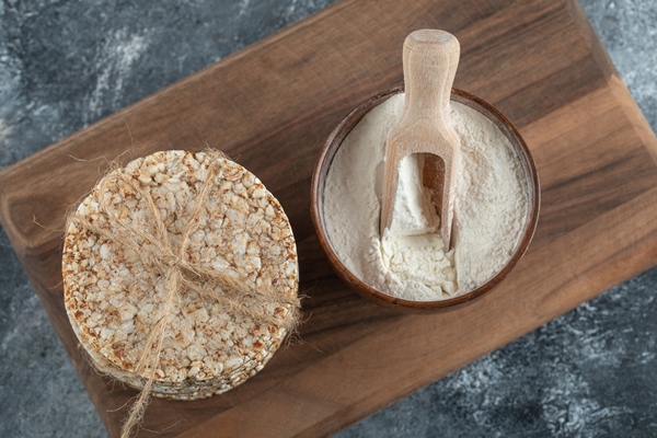 stack of rice cakes and bowl of flour on wooden board - Овсяная каша по-шотландски