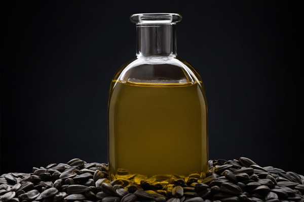 sunflower oil with seeds and a flower on a black background - Фруктовые оладьи на закваске, постный стол