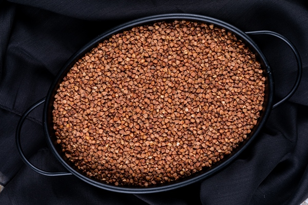 top view buckwheats in pot on black cloth background horizontal - Гречневая каша с молоком в мультиварке