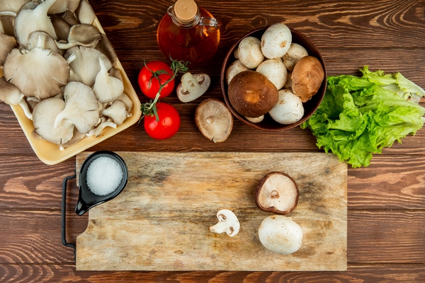 top view of fresh mushrooms in bowl and tomatoes with lettuce and a wood board with salt and sliced mushrooms on wood rustic - Суп с фрикадельками из шампиньонов или вешенок