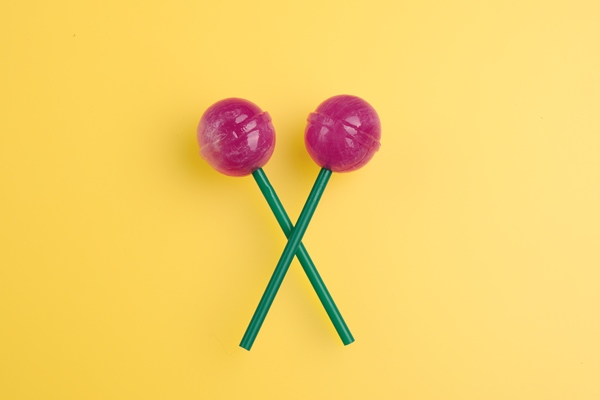 two big bright tasty lollipops on green sticks on yellow pastel background with copy space - Хозяйке на заметку: словарь кондитера