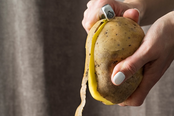 woman peeling raw potatoes - Кугель овощной в мультиварке