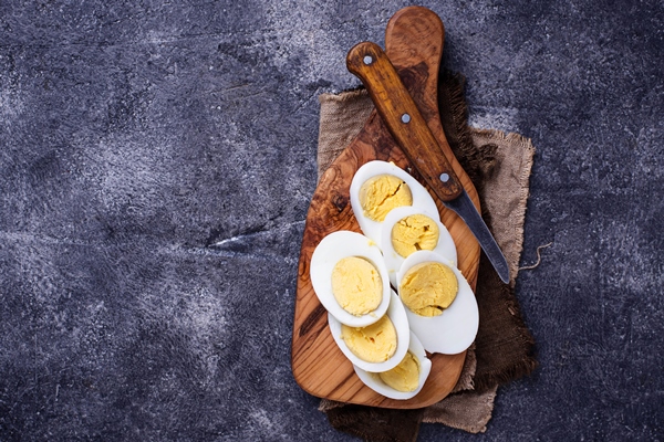 boiled sliced chicken eggs cutting board - Тарталетки с крабовыми палочками, огурцом и яйцом