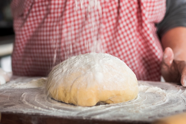 close up flour falling kneaded dough - Булочки с корицей