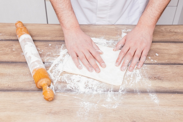 close up male baker preparing dough wooden table - Булочки из слоёного теста