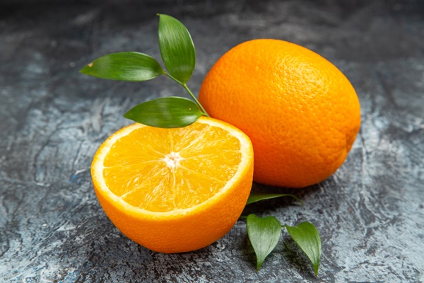 close up view cut half whole fresh orange with leaves gray background stock photo - Начинка апельсиновая с ромом для блинчиков