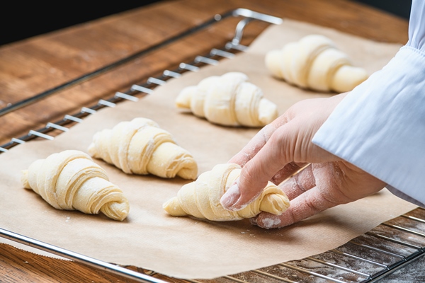 cook puts croissants baking sheet table with ingredients - Слоёные рожки
