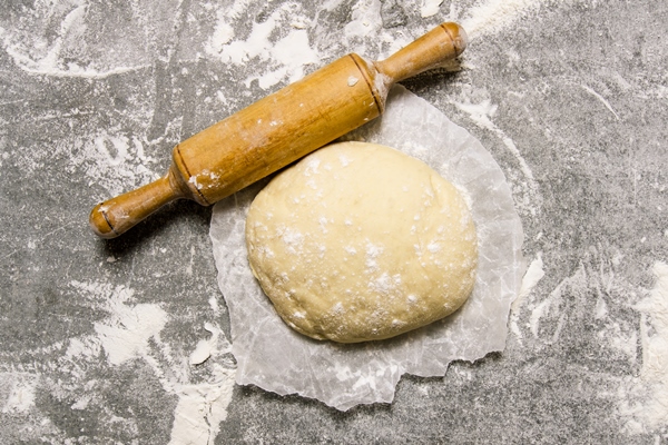 dough paper with rolling pin stone background top view - Булочки с фруктовой начинкой