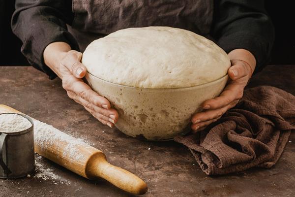 female chef holding bowl with pizza dough - Булочки с маком