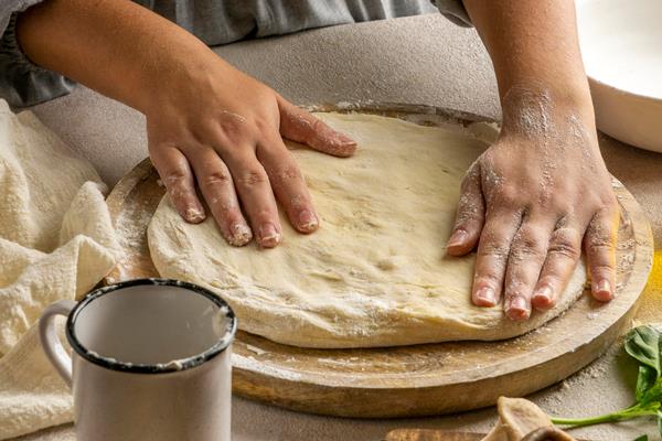 female chef stretching pizza dough - Постная пицца с креветками, лососем и оливками