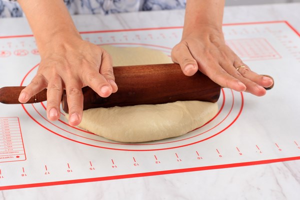 female hand rolled pizza bread dough with rolling pin white table sprinkled with flour baking step by step kitchen - Булочки с маком
