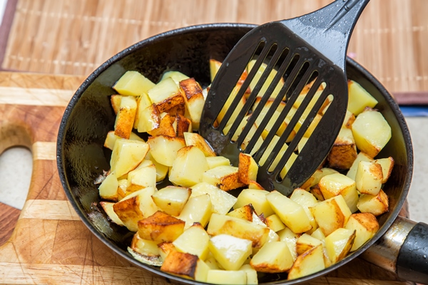 fresh potatoes fried pan with oil stirring rod close up - Жареный картофель