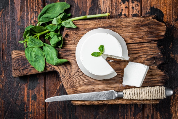 fresh ricotta cream cheese wooden board with basil dark wooden background top view - Тарталетки с сырным набором и овощами