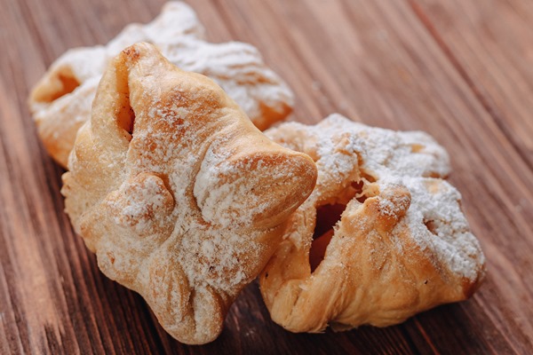 fresh sweet pastry is sprinkled with sugar powder wooden sur - Булочки из слоёного теста