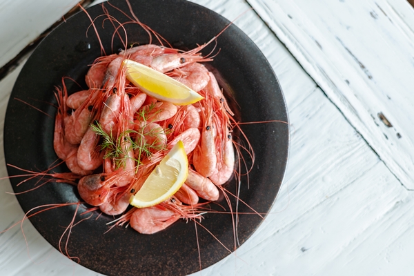 high angle shot plate botan shrimps with lemon white wooden surface - Паста с креветками и помидорами
