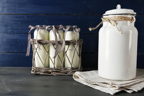 milk can glass bottles color wooden background - Булочки с корицей