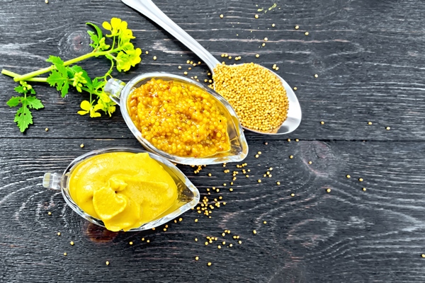 mustard sauce dijon mustard two glass saucepans yellow flower seeds spoon background wooden board from - Блинчики с картофелем
