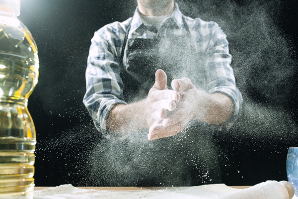 professional male cook sprinkles dough with flour - Постная пицца с креветками, лососем и оливками