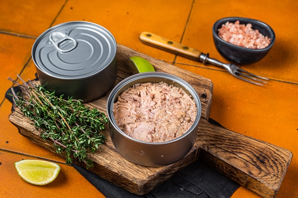 tin with canned tuna fillet meat olive orange background top view - Тарталетки с морепродуктами