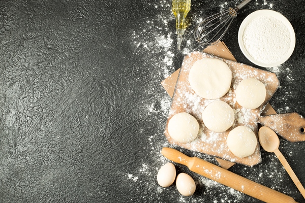 top view dough balls wooden plate with cooking ingredients black background - Пончики дрожжевые с начинкой