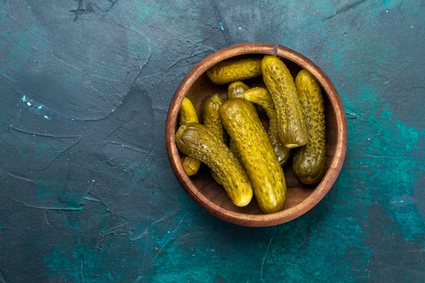 top view salty pickles inside round brown pot dark blue surface - Тарталетки с крабовыми палочками, огурцом и яйцом