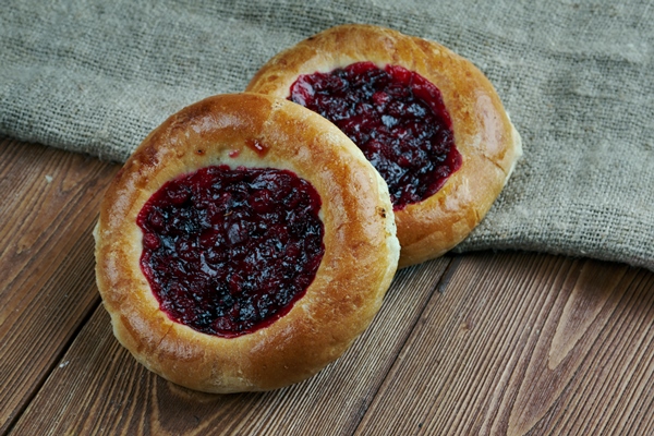 vatrushkai patties with cowberry russian pastry on a wood background - Булочки с фруктовой начинкой