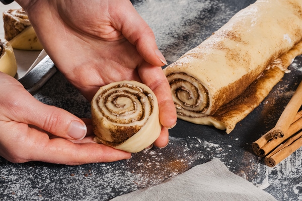 woman put dough rolls pan prepare buns with cinnamon baking - Булочки с корицей