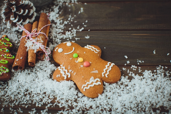 wooden background with gingerbread man cones snow top view closeup - Кулинарные традиции: пряники