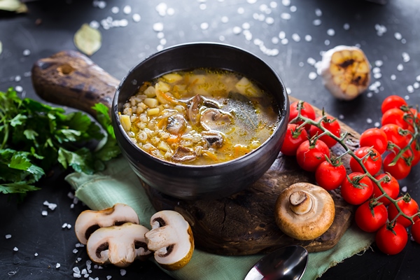 wooden cutting kitchen board soup with mushrooms barley porridge cherry tomatoes cutlery - Рассольник с шампиньонами