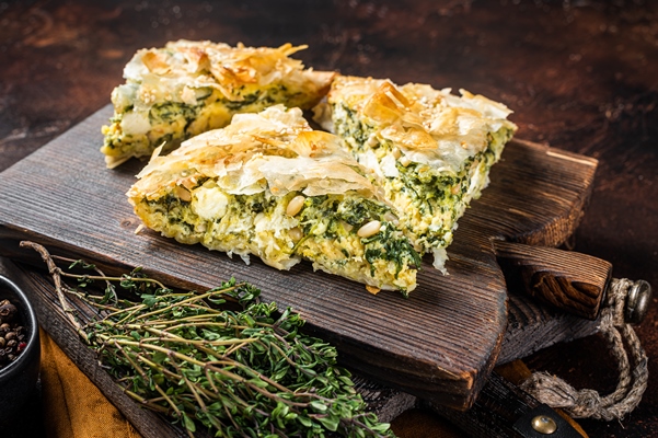 spanakopita greek pie with spinach cheese wooden board dark background top view - Спанакопита с тахини