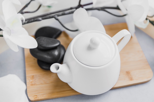 teapot near pebbles blooming twig - Цитрусовый чай