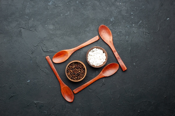 top view bowls with sea salt black pepper around wooden spoons dark table with copy place - Гороховый суп с лимоном и гренками