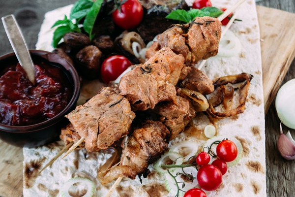 pork shish kebab with vegetables tomato sauce closeup wooden table - Шашлык из свинины с маринованным луком