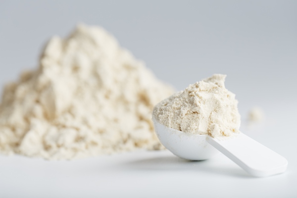 whey protein isolate with measuring spoon white background - Конфеты из сухого молока
