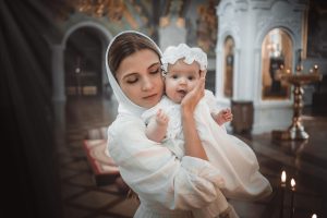 a mother with a small child in a temple or church prays near an icon and candles or came to a divine service in the russian orthodox church the baptism of a baby - «Любовь никогда не перестаёт»: христианская семья в вечном измерении